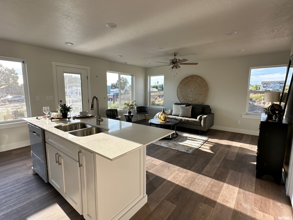 Kitchen with stainless steel dishwasher, a textured ceiling, dark hardwood flooring, light countertops, and ceiling fan