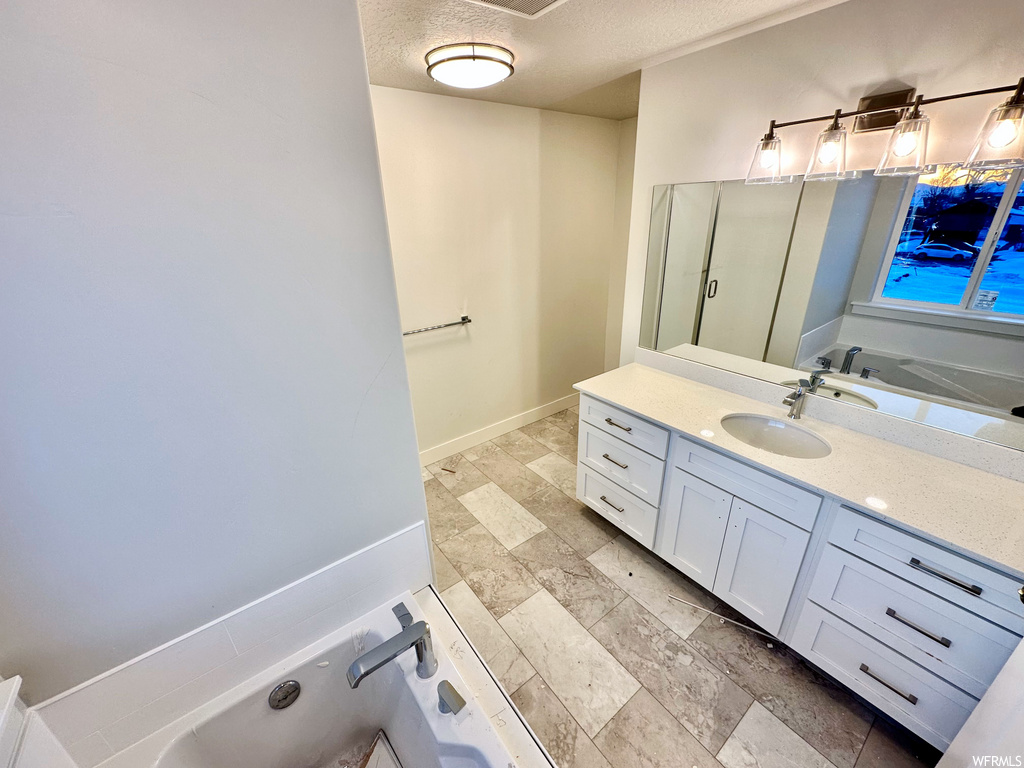 bathroom featuring tile flooring, large vanity, mirror, and a bath