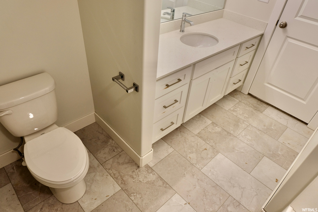 half bath with tile floors, vanity, and toilet