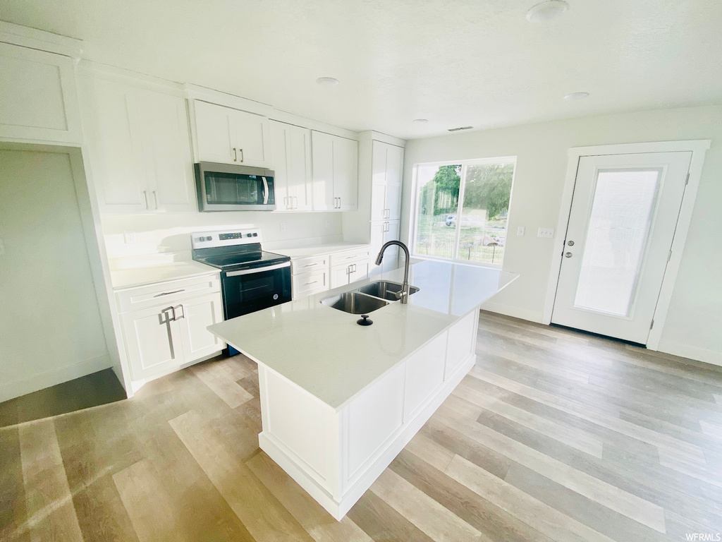 Kitchen featuring natural light, microwave, electric range oven, white cabinets, light flooring, and light countertops