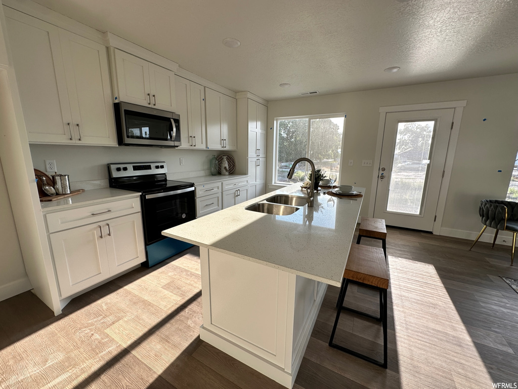 Kitchen featuring white electric range oven, light countertops, hardwood floors, and white cabinets