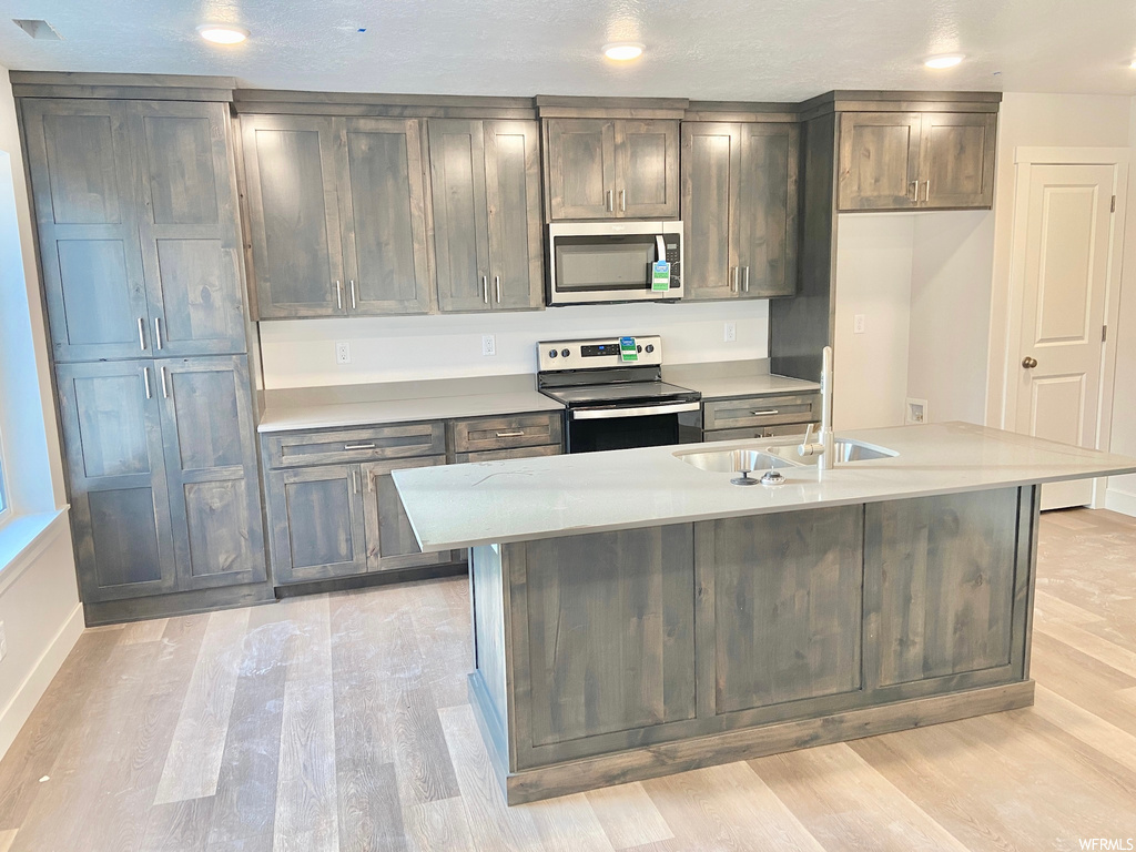 Kitchen with microwave, electric range oven, light countertops, and light hardwood floors