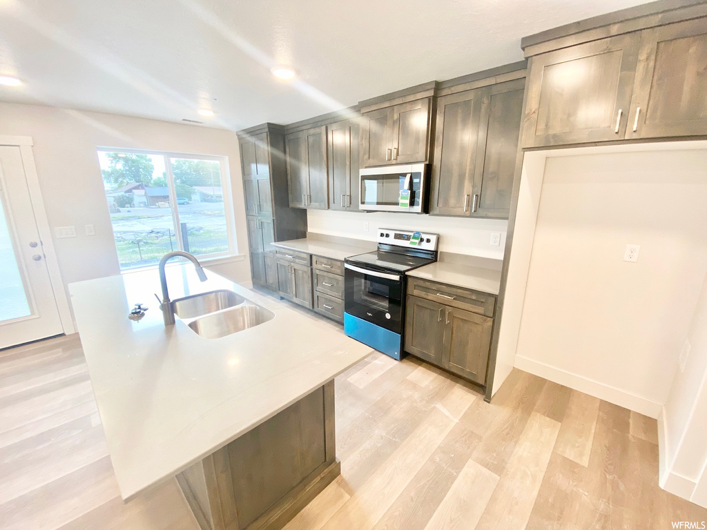 Kitchen featuring natural light, electric range oven, microwave, light countertops, and light flooring