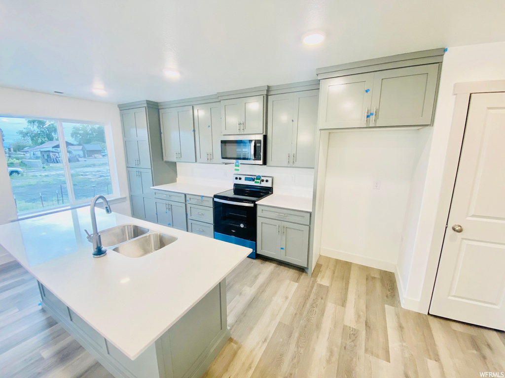 Kitchen with a center island, natural light, microwave, electric range oven, light hardwood floors, light countertops, and white cabinetry