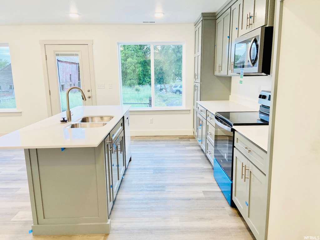 Kitchen featuring natural light, electric range oven, microwave, light countertops, and light parquet floors