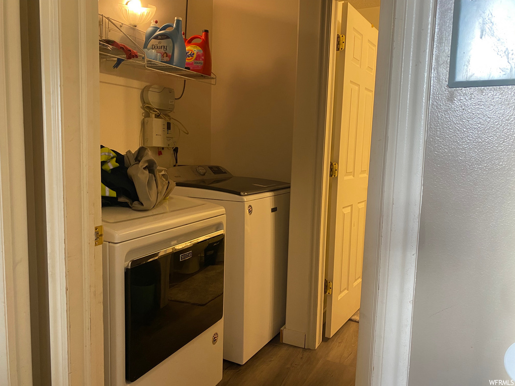 clothes washing area with hardwood flooring and washer / dryer