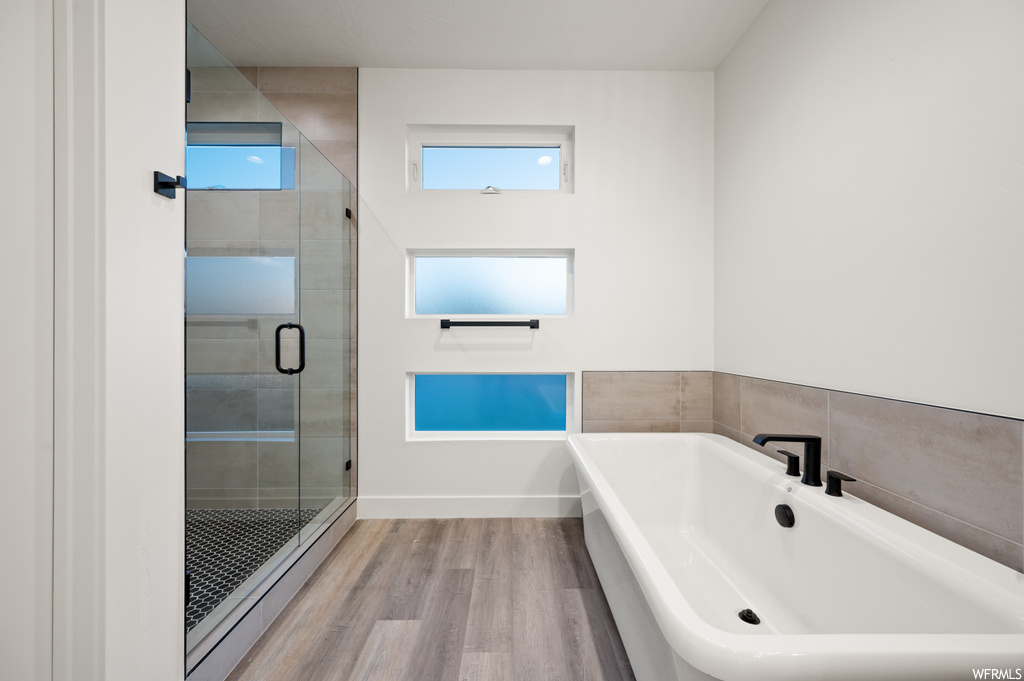 Bathroom featuring light hardwood flooring and separate shower and tub enclosures