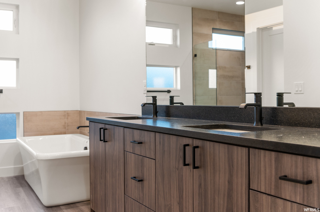 Bathroom with double vanity, hardwood floors, a tub, and mirror
