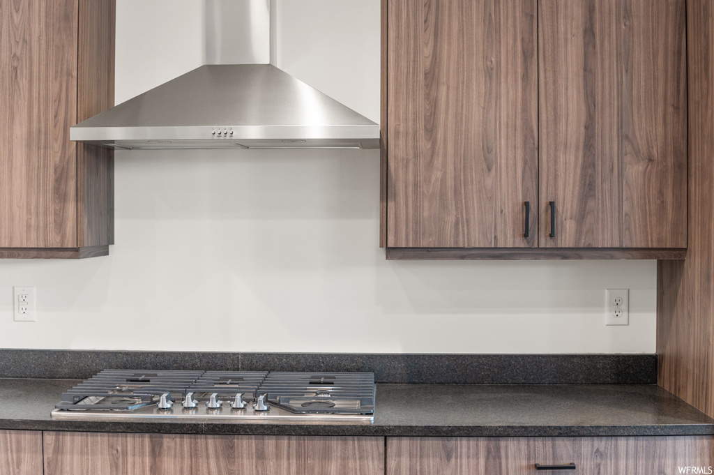 Kitchen with stainless steel gas cooktop and wall chimney range hood