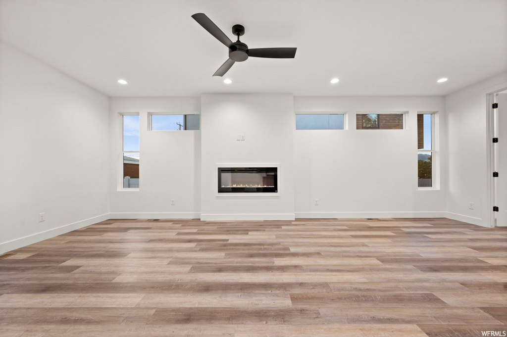 Hardwood floored living room featuring a healthy amount of sunlight and ceiling fan