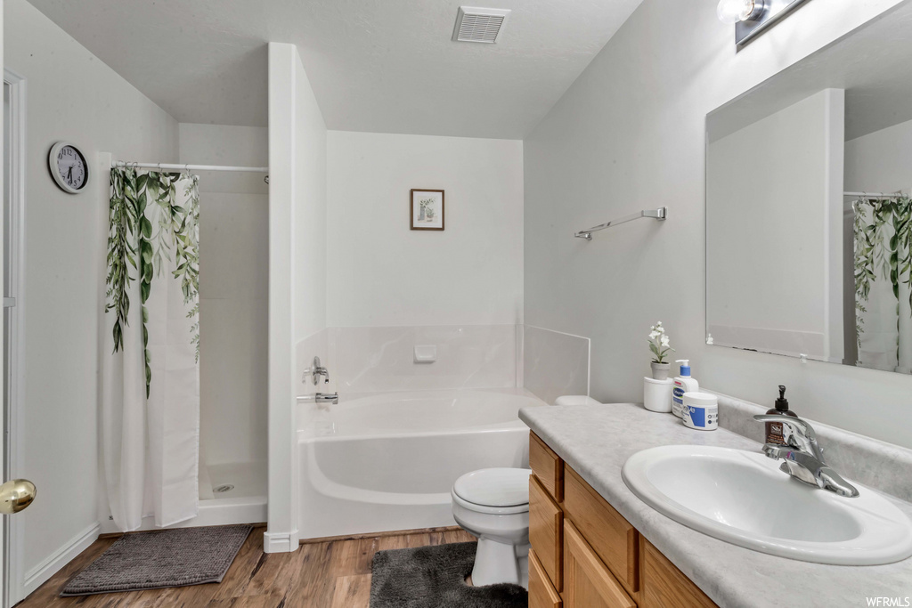 full bathroom featuring hardwood flooring, toilet, vanity, shower curtain, independent shower and bath, and mirror