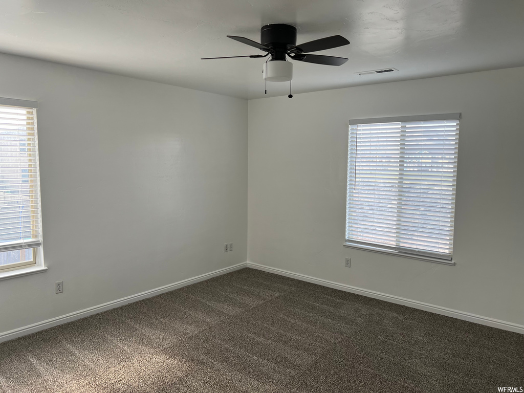 empty room with natural light, carpet, and a ceiling fan
