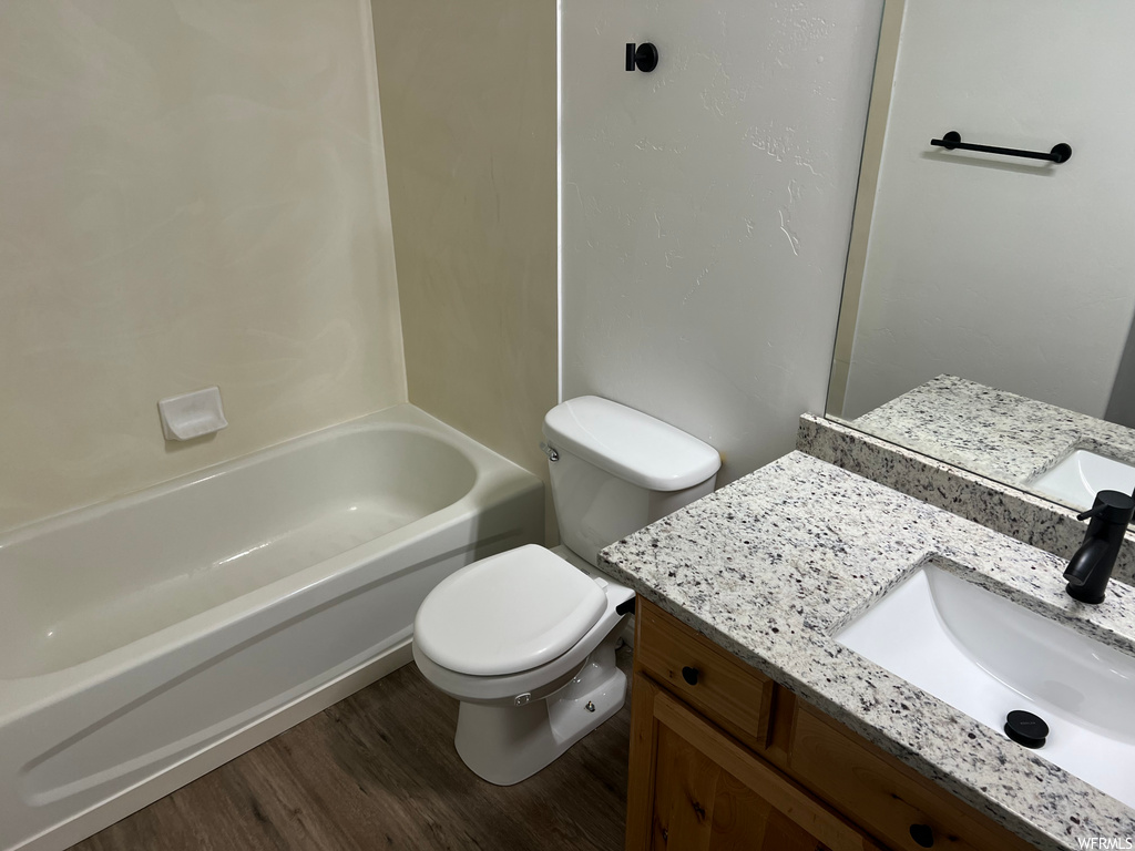 full bathroom featuring hardwood flooring, mirror, shower / washtub combination, vanity, and toilet