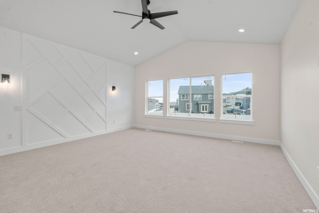 spare room featuring carpet, lofted ceiling, and natural light