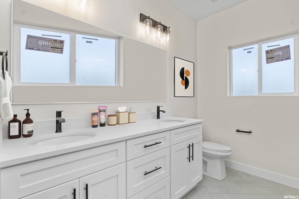 half bath with tile flooring, his and hers vanities, and toilet