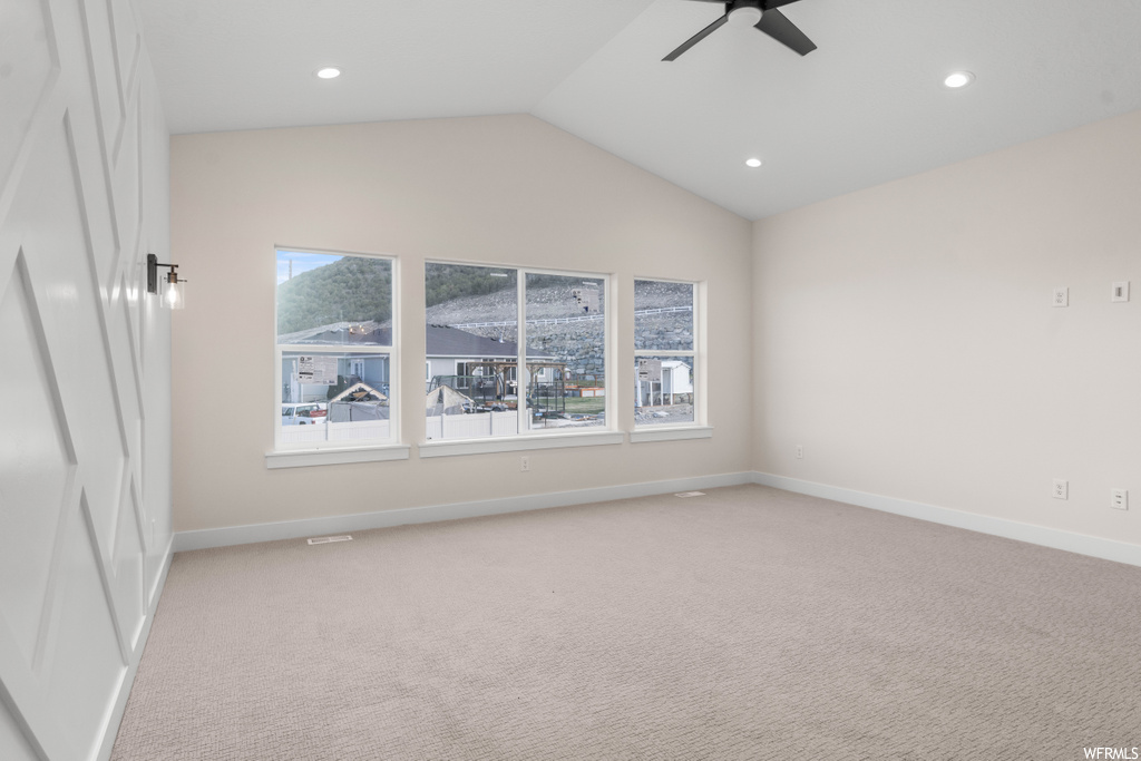 empty room featuring lofted ceiling, carpet, and a ceiling fan