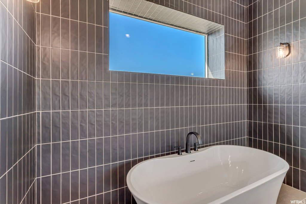Bathroom featuring a bathing tub and tile walls