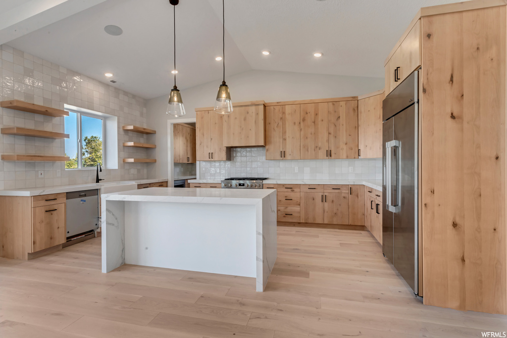 Kitchen featuring backsplash, light hardwood floors, a center island, and light brown cabinets
