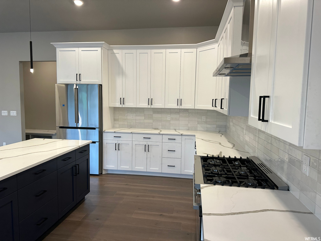 kitchen with wood-type flooring, gas range oven, refrigerator, range hood, light countertops, white cabinets, and pendant lighting