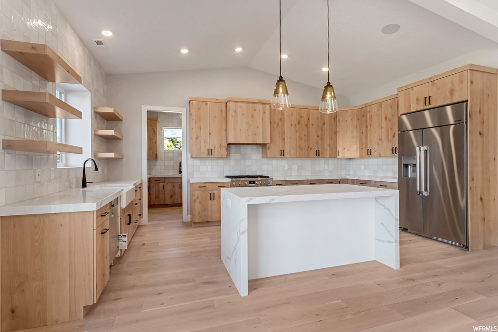 Kitchen with a center island, tasteful backsplash, light hardwood flooring, light brown cabinets, and built in fridge