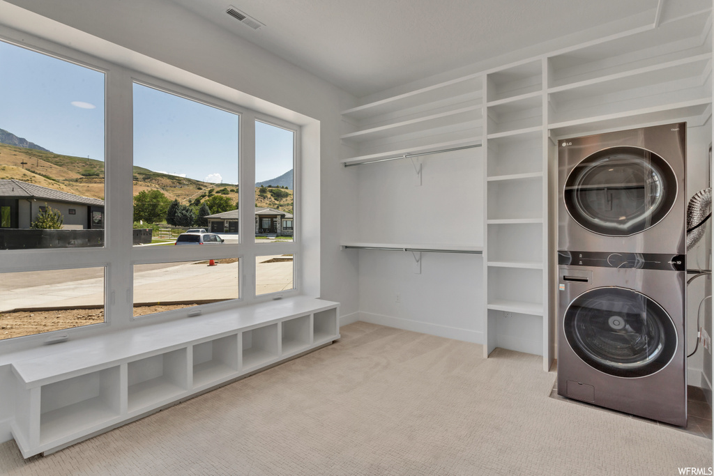 Laundry room with light colored carpet and stacked washer / drying machine