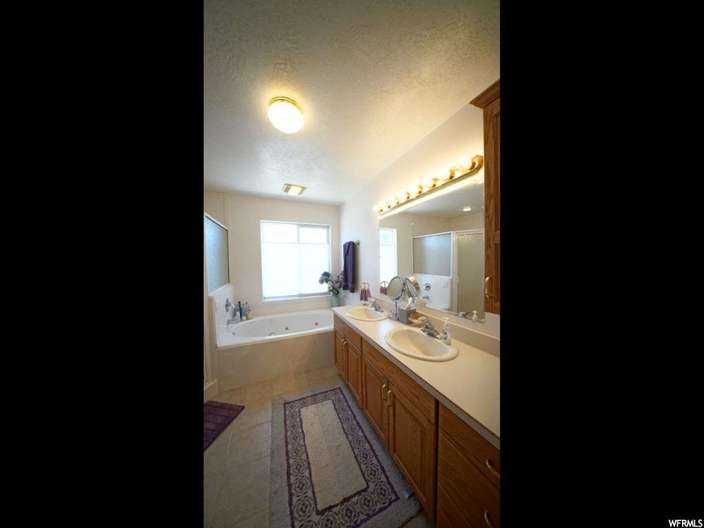 bathroom with natural light, a bathing tub, mirror, and vanity with extensive cabinet space