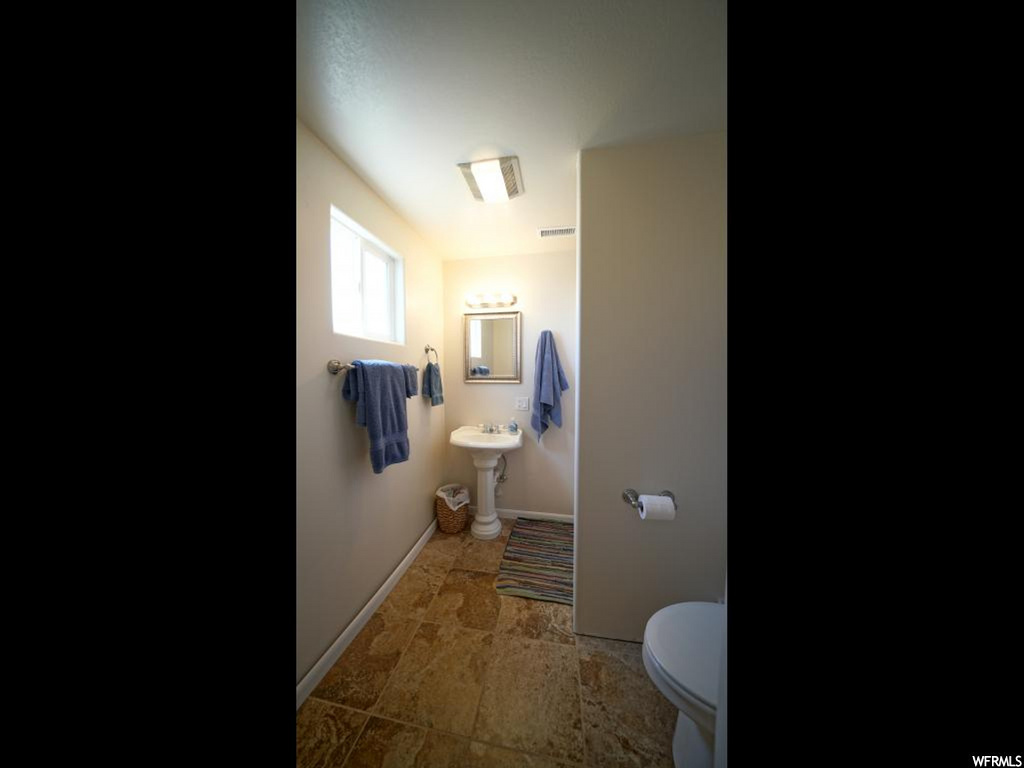 half bathroom featuring tile floors, sink, and toilet
