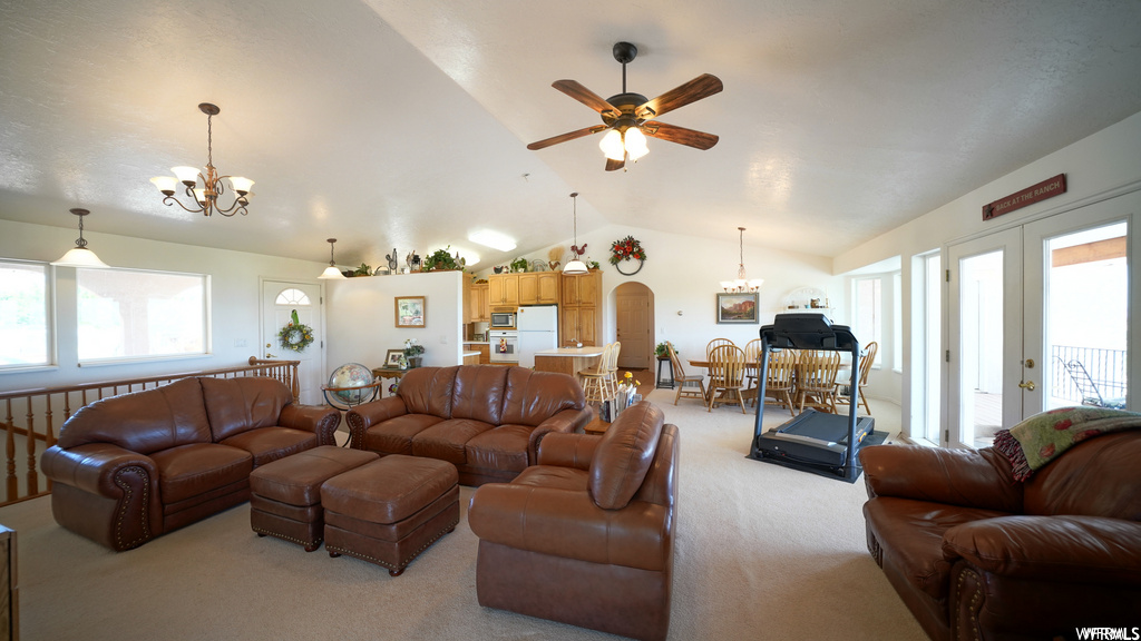 carpeted living room featuring natural light, french doors, a breakfast bar area, a ceiling fan, and vaulted ceiling