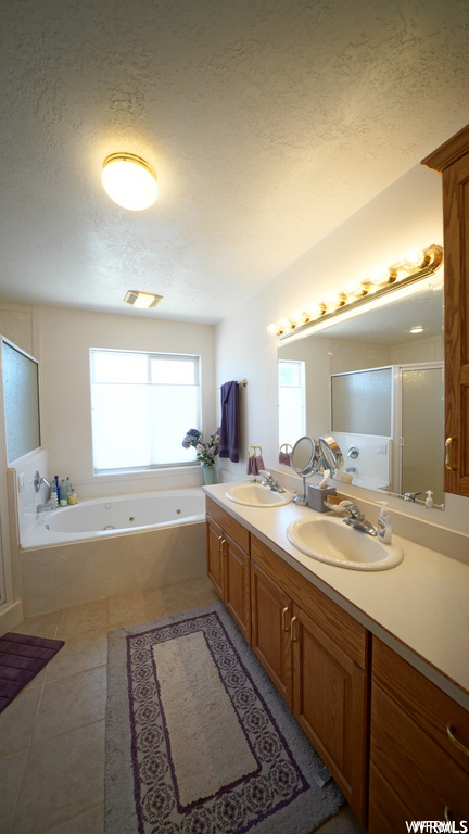 bathroom featuring natural light, tile flooring, double vanity, mirror, and a washtub