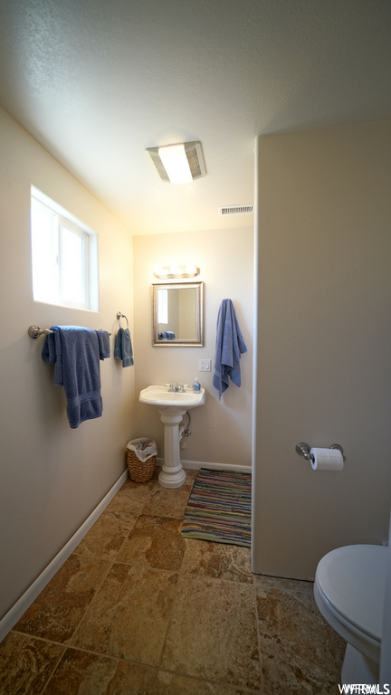 half bath with tile flooring, sink, mirror, and toilet