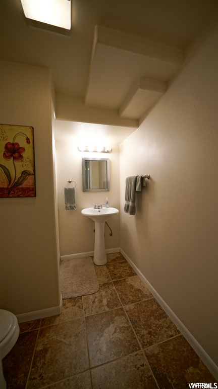 half bathroom with tile floors, sink, mirror, and toilet