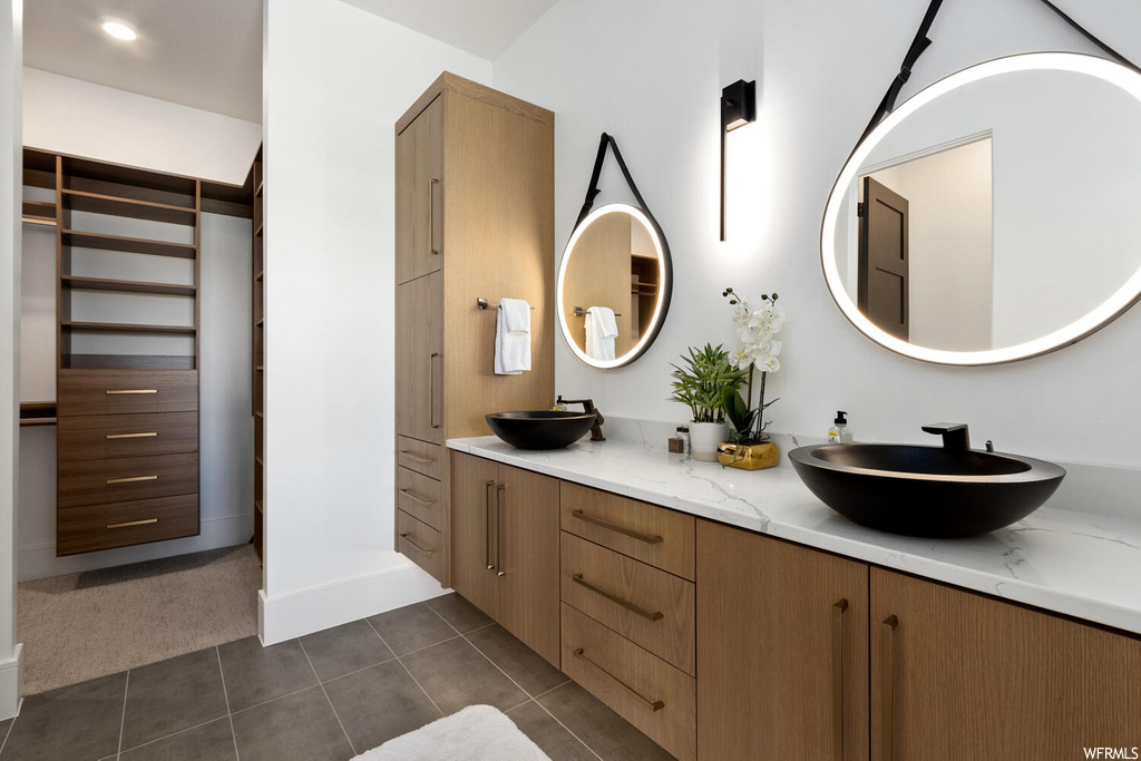 bathroom featuring tile flooring, double vanities, and multiple mirrors