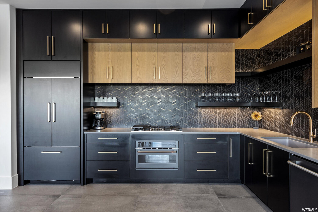 bar featuring stainless steel oven, dishwasher, gas stovetop, light tile floors, and dark brown cabinetry