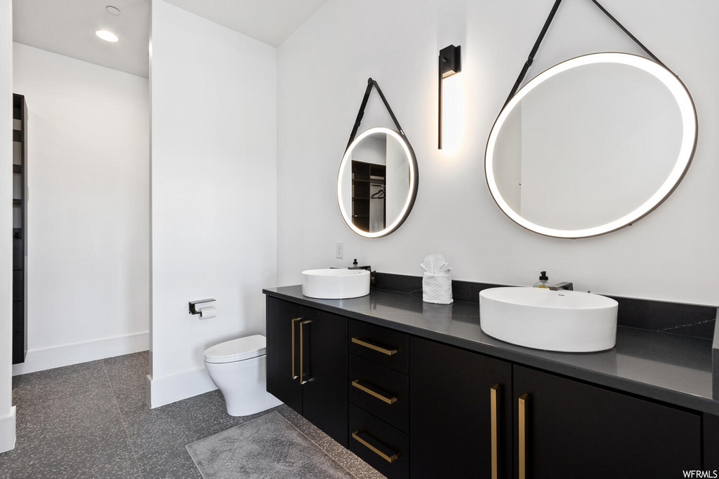 half bathroom featuring mirror, dual vanities, and toilet