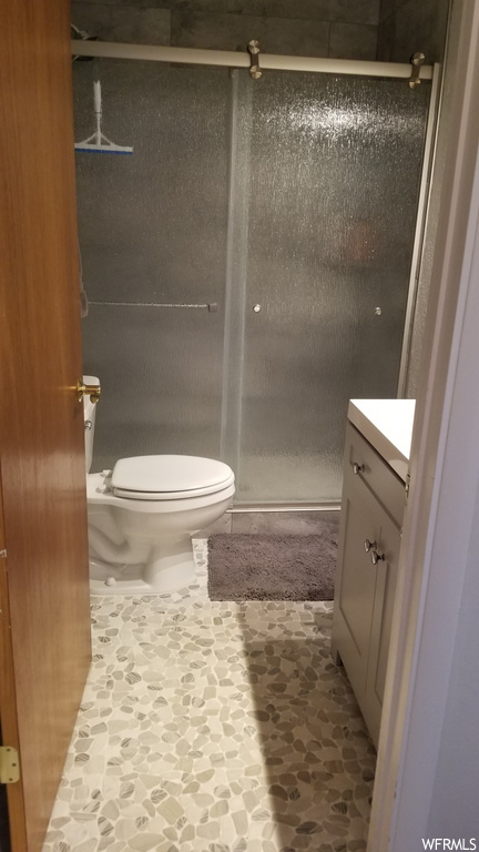 bathroom featuring tile flooring, a shower, toilet, and vanity