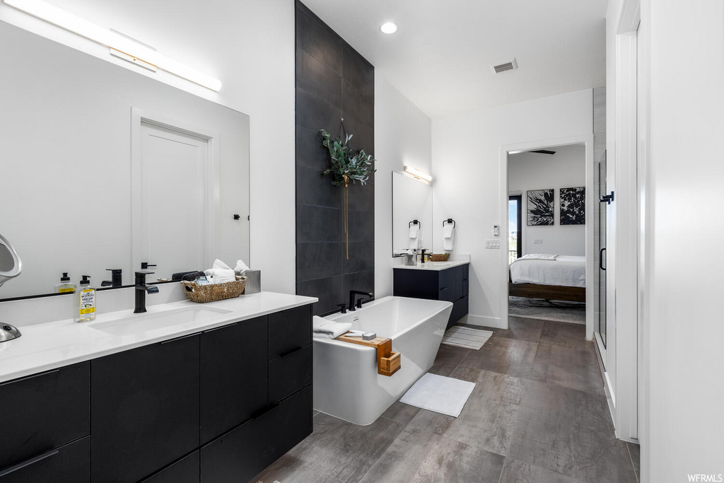 bathroom featuring a washtub, mirror, and vanity