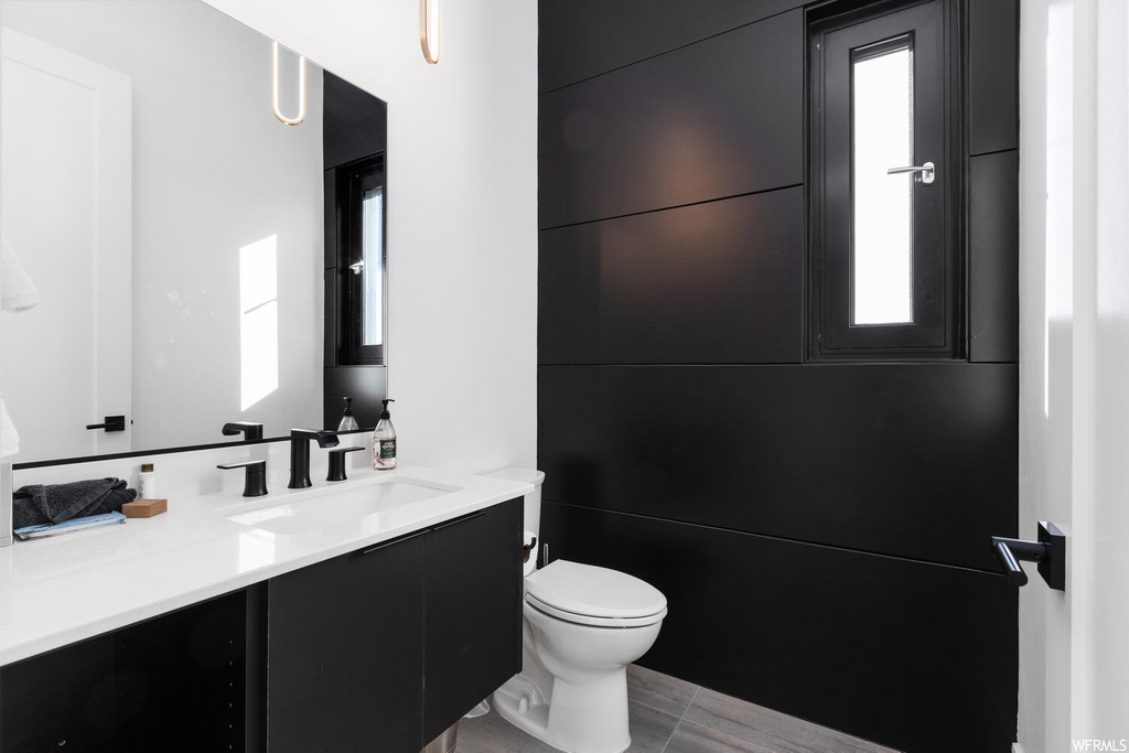 half bathroom featuring tile floors, natural light, mirror, toilet, and vanity
