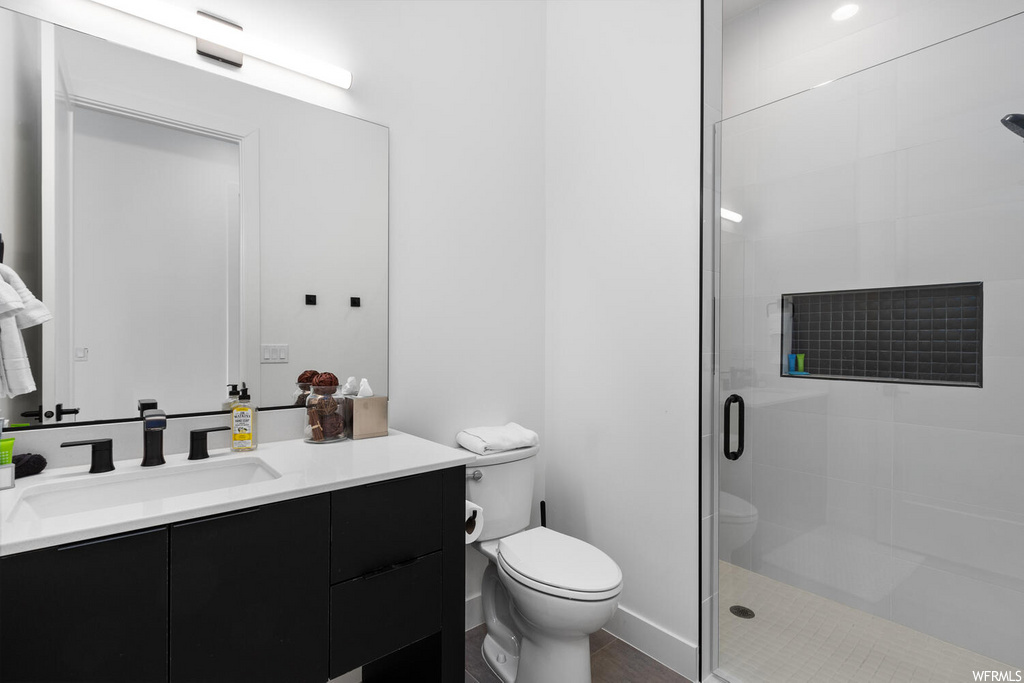 full bathroom featuring mirror, shower with shower door, vanity, and toilet