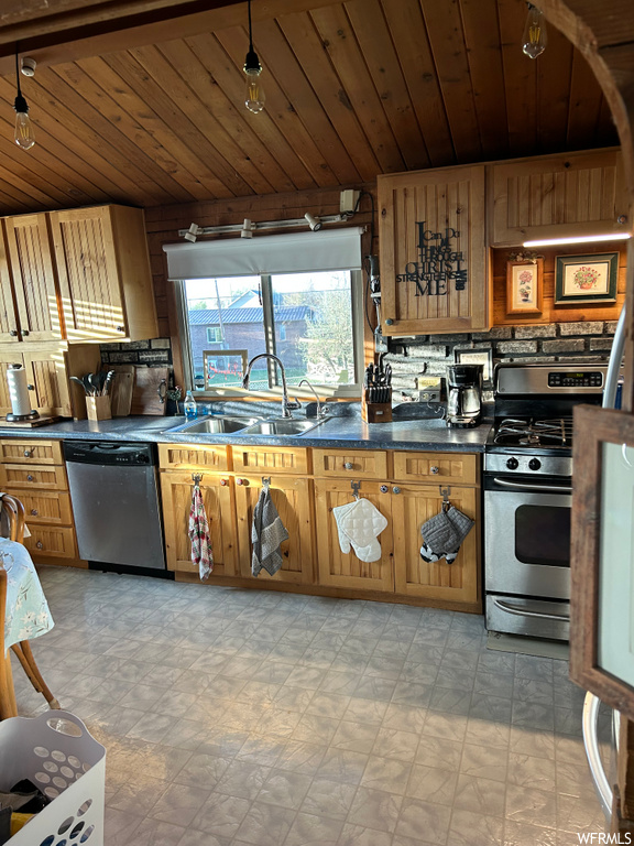 kitchen featuring natural light, gas range oven, dishwasher, brown cabinetry, and light tile floors