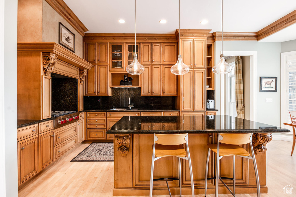 Kitchen featuring a breakfast bar, pendant lighting, a center island, and light hardwood / wood-style floors