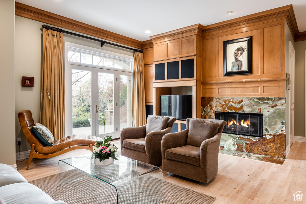 Living room featuring french doors, light hardwood / wood-style flooring, ornamental molding, and a tiled fireplace