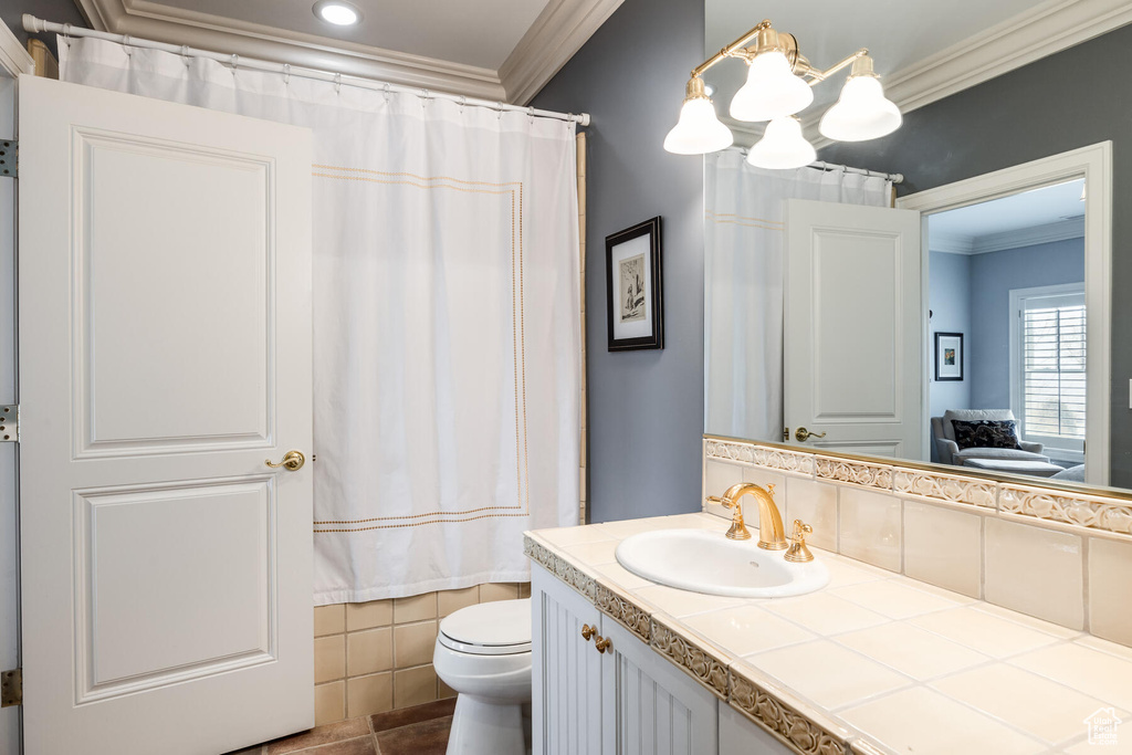 Bathroom featuring toilet, crown molding, vanity with extensive cabinet space, and tile flooring