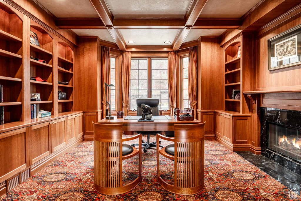 Office space with a high end fireplace, coffered ceiling, beamed ceiling, built in features, and wood walls