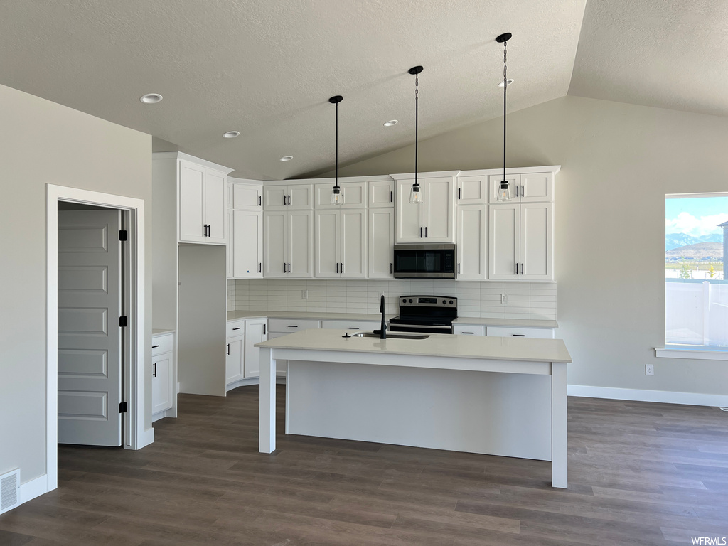 Kitchen featuring white cabinetry, decorative light fixtures, a textured ceiling, stainless steel appliances, hardwood floors, light countertops, vaulted ceiling, and backsplash