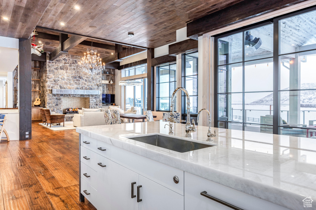 Kitchen with a sink, wood ceiling, light stone counters, wood finished floors, and open floor plan