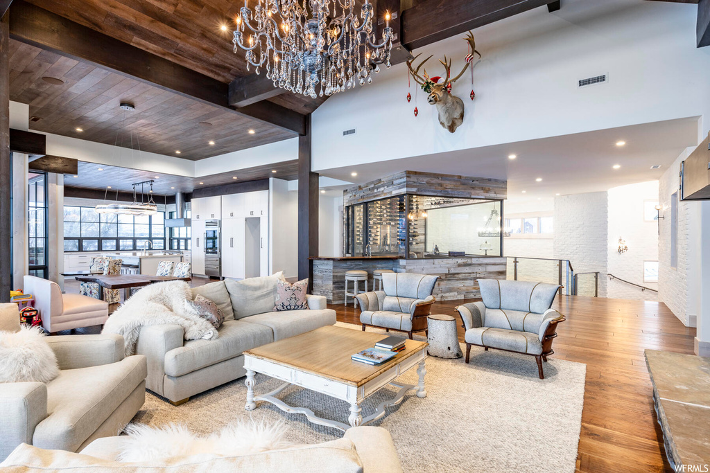 Living room featuring a chandelier, a towering ceiling, wood ceiling, and light hardwood / wood-style flooring