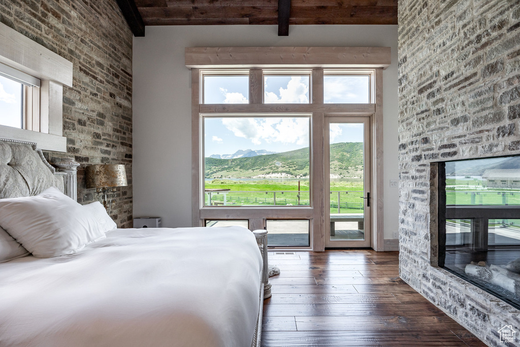 Bedroom with hardwood / wood-style flooring, access to outside, and beam ceiling