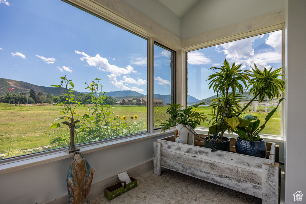 Sunroom featuring a mountain view, lofted ceiling, and baseboards