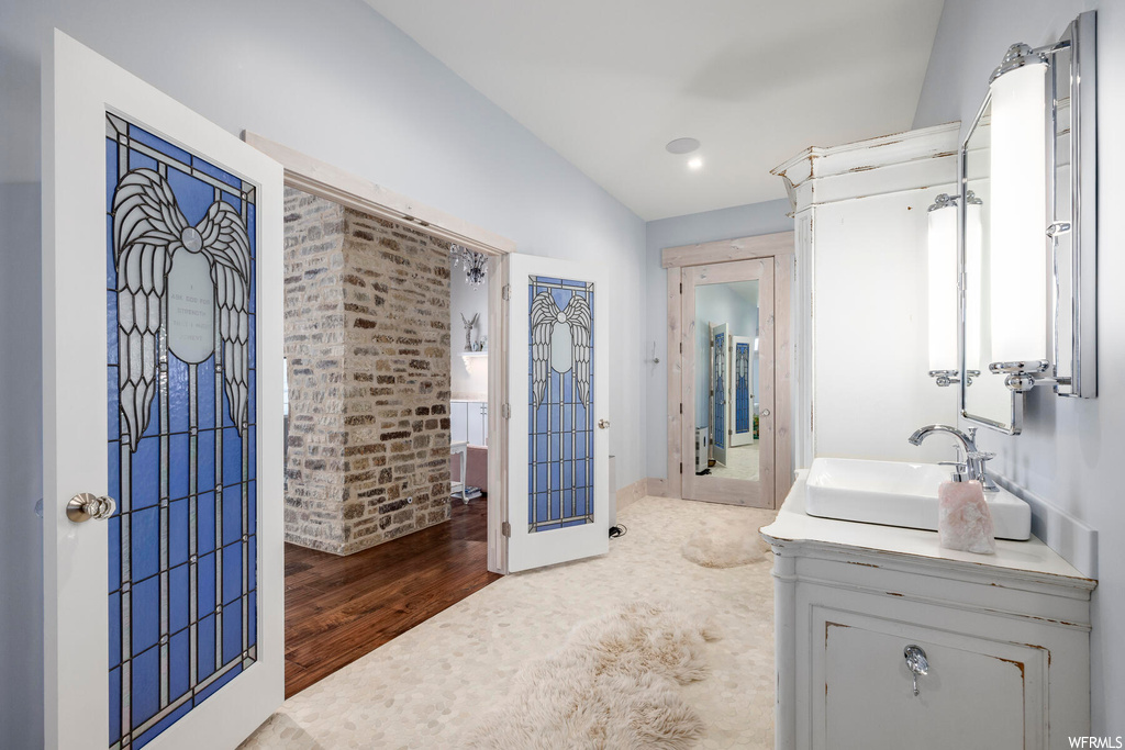 Bathroom featuring walk in shower, wood-type flooring, vanity, and lofted ceiling