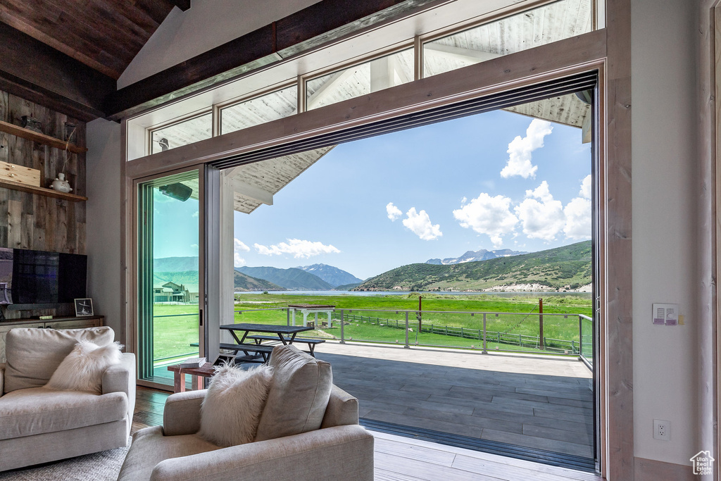 Doorway to outside featuring a mountain view, lofted ceiling, wood-type flooring, and healthy amount of natural light